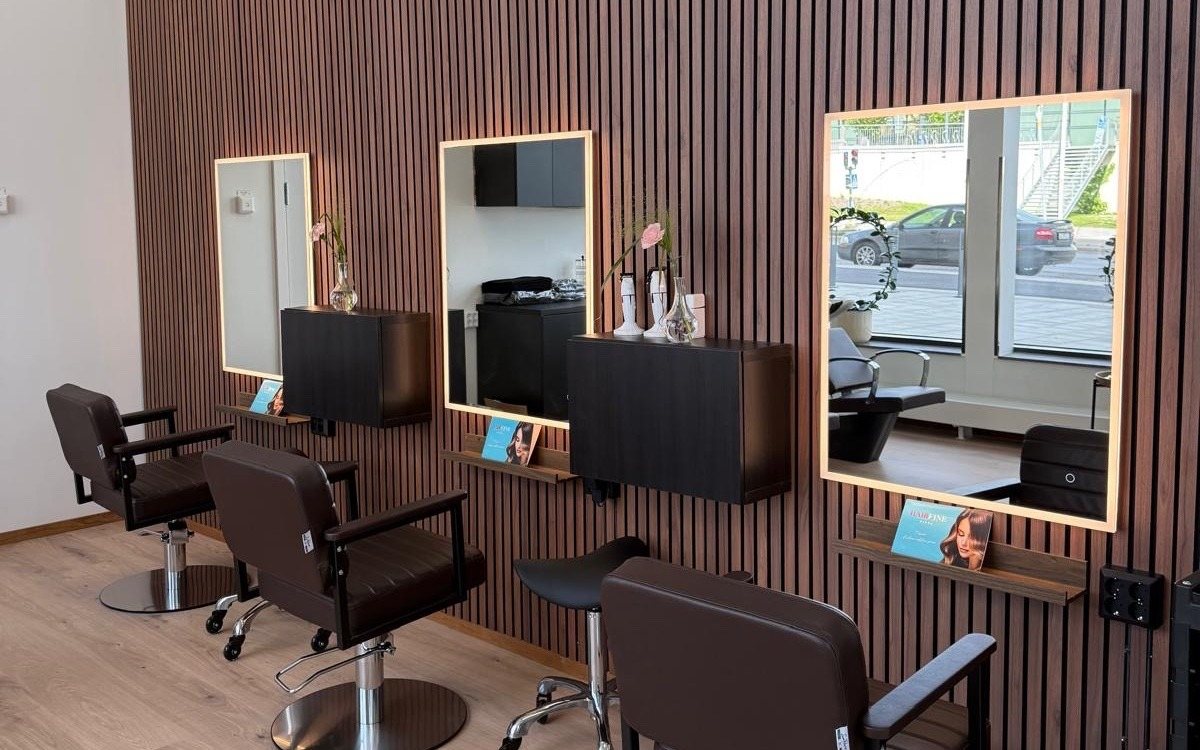 Arbetsplatser med belysta speglar mot en träpanel i Hairfine Kista